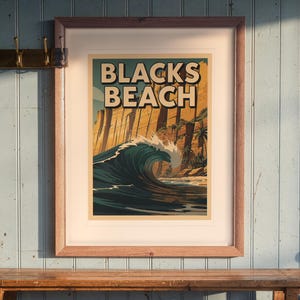 Blacks Beach Surf Travel Poster print in a Red Oak frame with a white mat, hanging above the bench in a beach cottage entryway.