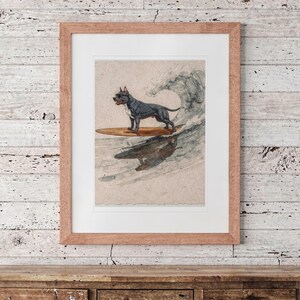 Pit Bull Surfing printable art, shown printed in a Red Oak frame with a white mat, hanging above the dresser in a surf shack bedroom.