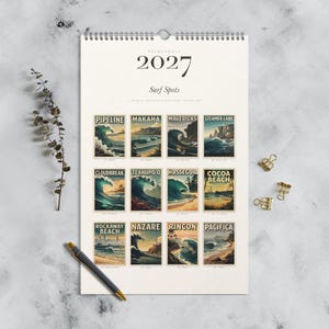 May include: A 2027 wall calendar titled Surf Spots featuring twelve vintage-style illustrations of famous surfing locations including Pipeline, Makaha, Mavericks, Steamer Lane, Cloudbreak, Teahupo'o, Hossegor, Cocoa Beach, Rockaway Beach, Nazare, Rincon, and Pacifica.