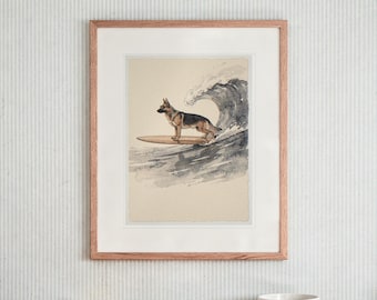 May include: A framed watercolor print featuring a German Shepherd standing on a wooden surfboard in front of a large, crashing ocean wave. The artwork is encased in a light-toned wooden frame with a white mat, displaying a neutral background.