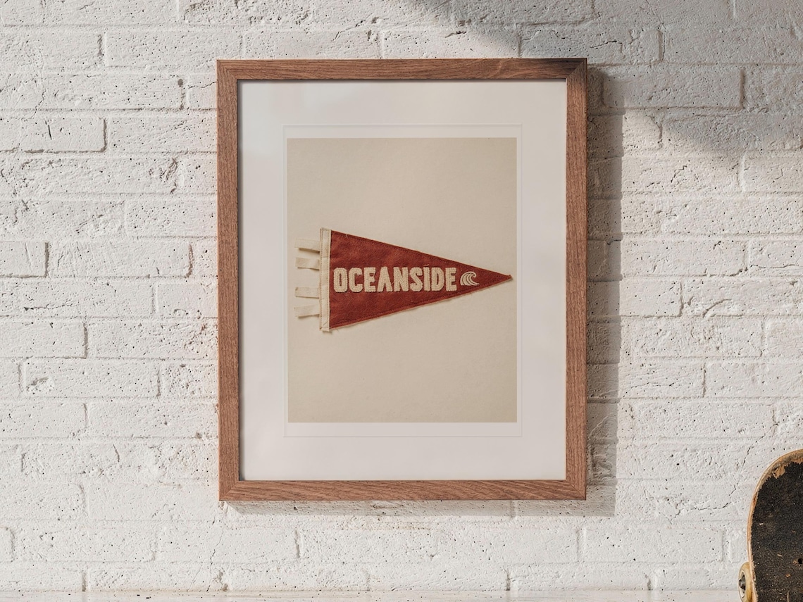Oceanside Surf Pennant print in a Red Oak frame with a white mat, hanging above the cubbies in a mudroom.