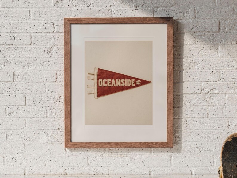 Oceanside Surf Pennant print in a Red Oak frame with a white mat, hanging above the cubbies in a mudroom.