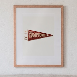 The Hamptons print in a Red Oak frame with a white mat, hanging above the headboard in a calm bedroom.
