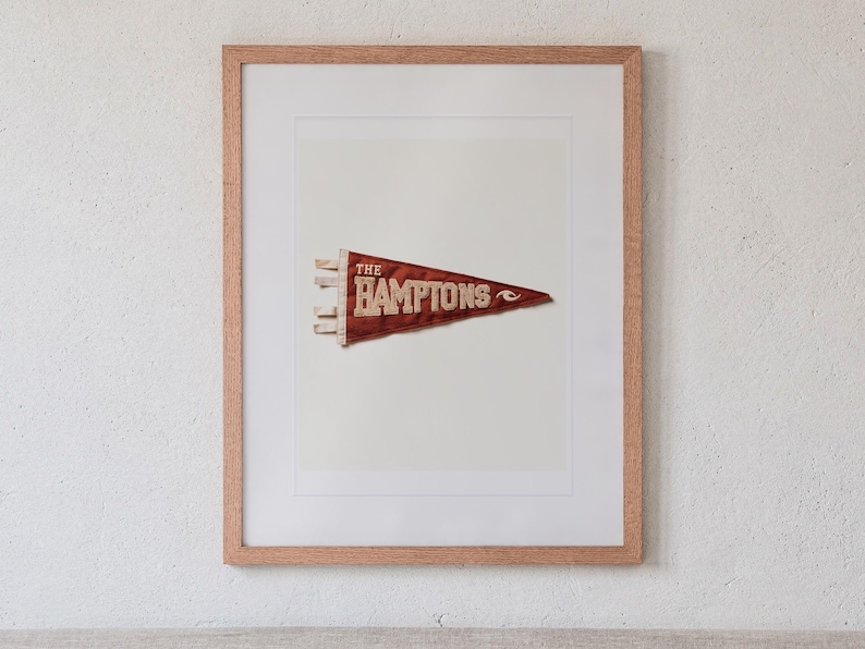 The Hamptons print in a Red Oak frame with a white mat, hanging above the headboard in a calm bedroom.