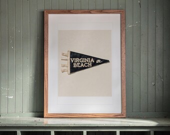 May include: A framed triangular felt pennant featuring the text VIRGINIA BEACH in white capital letters, accompanied by a white wave graphic. The pennant is dark blue with three white ties on the left side, displayed within a light wood frame.