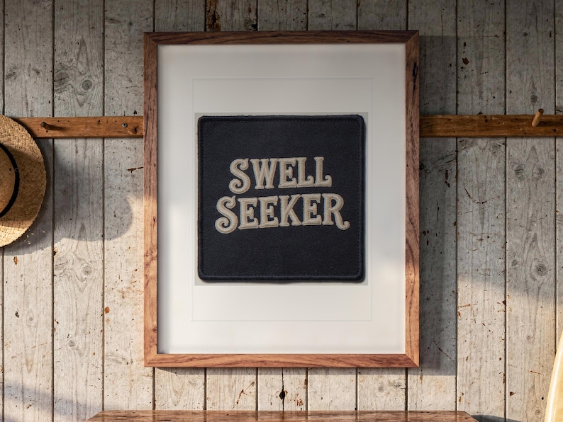 Swell Seeker Patch print in a Red Oak frame with a white mat, hanging above the dresser in a surf shack bedroom.