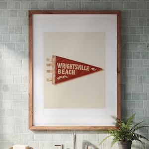 Wrightsville Beach Surf Pennant print in a Red Oak frame with a white mat, hanging above the vanity in a bright bathroom.