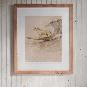 Yellow Labrador Surfing print in a Red Oak frame with a white mat, hanging above the bench in a breakfast nook.