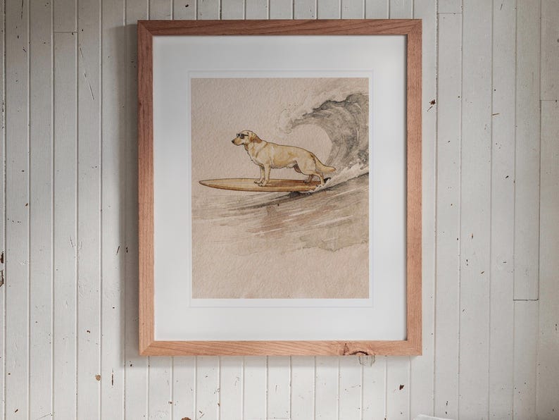 Yellow Labrador Surfing print in a Red Oak frame with a white mat, hanging above the bench in a breakfast nook.