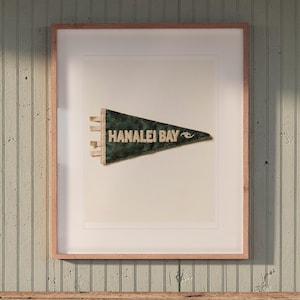 Hanalei Bay Surf Pennant print in a Red Oak frame with a white mat, hanging above the bench in a beach cottage entryway.