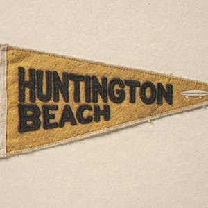 Huntington Beach Vintage Surf Pennant Print framed in a beach-style living room setting