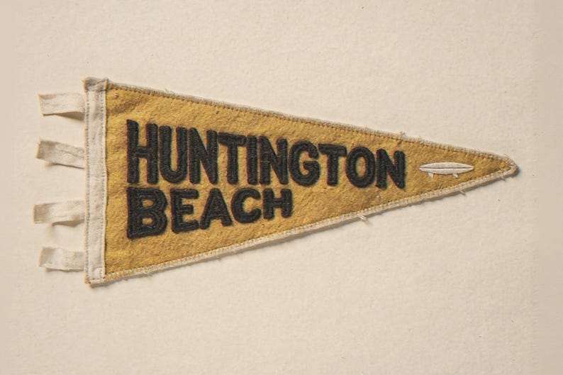 Huntington Beach Vintage Surf Pennant Print framed in a beach-style living room setting
