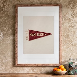 Miami Beach print in a Red Oak frame with a white mat, hanging above the vanity in a bright bathroom.