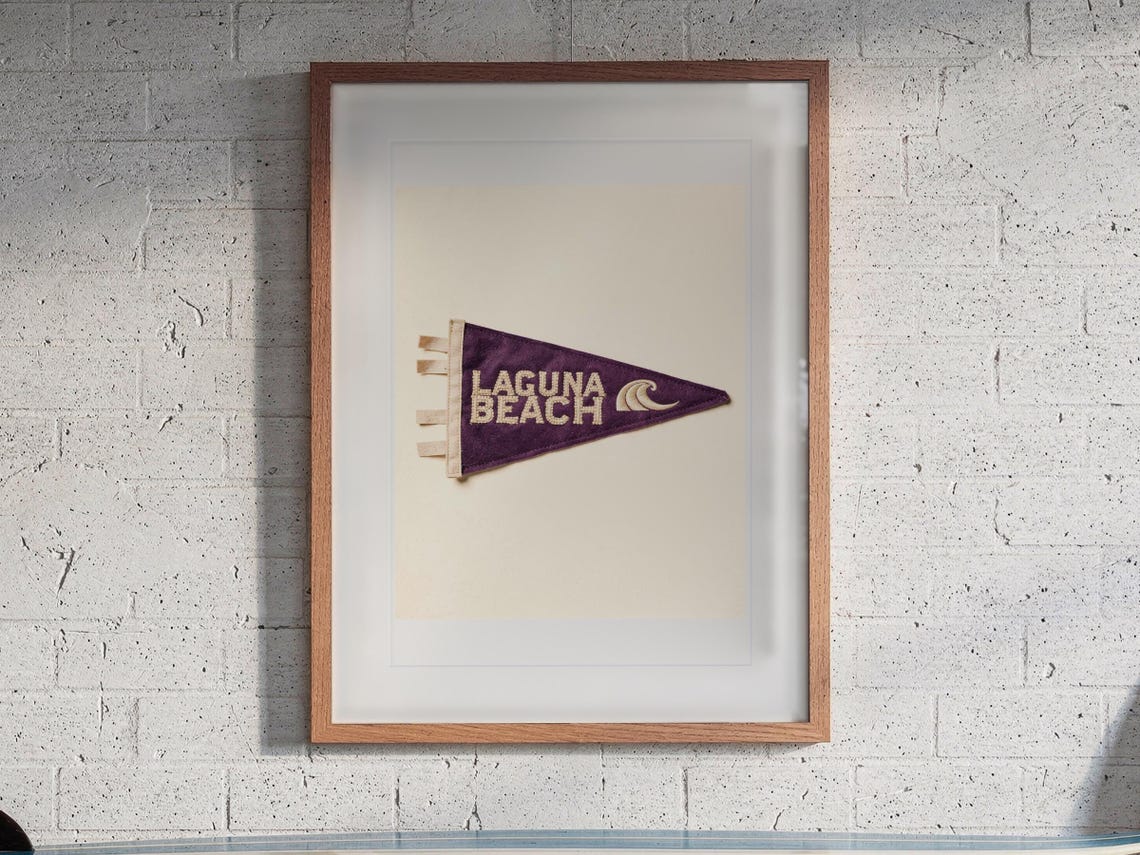 Laguna Beach print in a Red Oak frame with a white mat, hanging above the workbench in a surf garage.