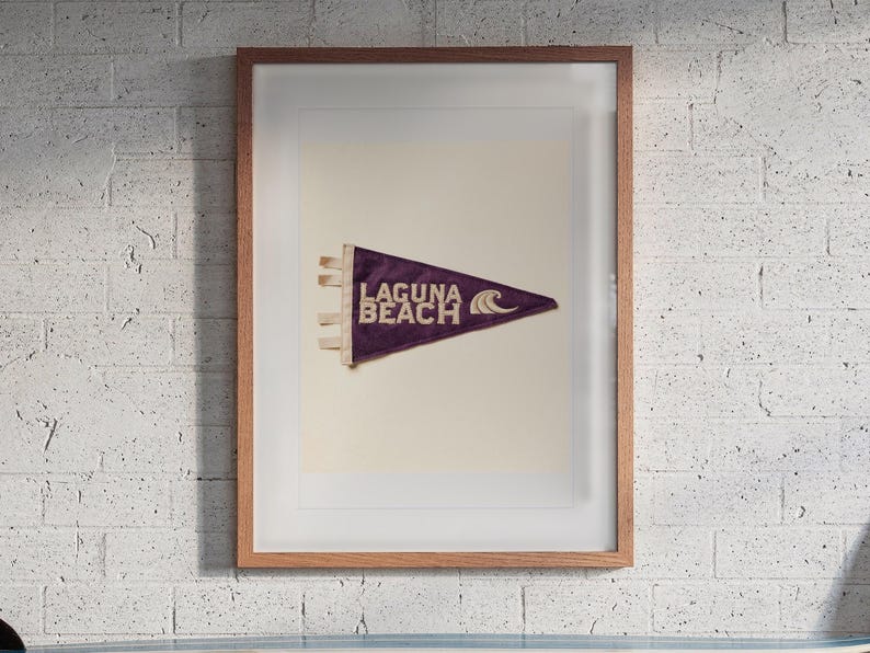 Laguna Beach print in a Red Oak frame with a white mat, hanging above the workbench in a surf garage.