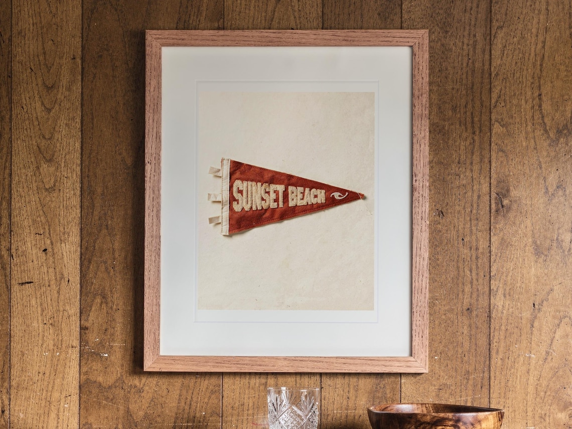 Sunset Beach print in a Red Oak frame with a white mat, hanging above the cabinet in a game room.