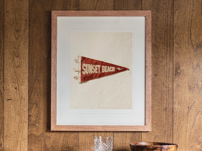 Sunset Beach print in a Red Oak frame with a white mat, hanging above the cabinet in a game room.