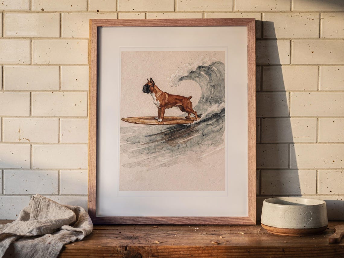 Boxer Surfing print in a Red Oak frame with a white mat, leaning on the shelf against the wall in a cottage kitchen.