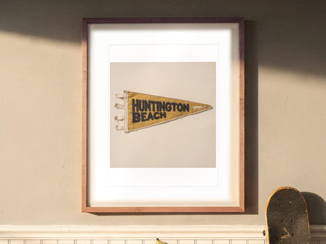 Huntington Beach Surf Pennant print in a Red Oak frame with a white mat, hanging above the sideboard in a dining room.