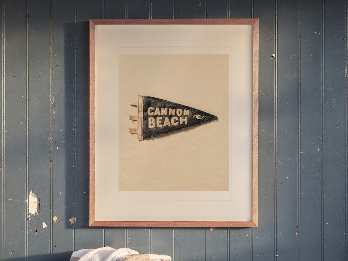 Cannon Beach print in a Red Oak frame with a white mat, hanging above the bench in a mudroom.