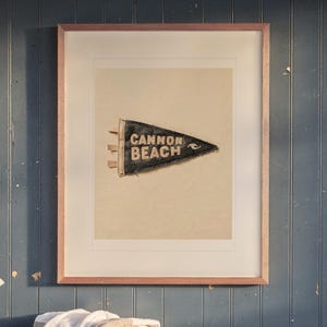 Cannon Beach print in a Red Oak frame with a white mat, hanging above the bench in a mudroom.