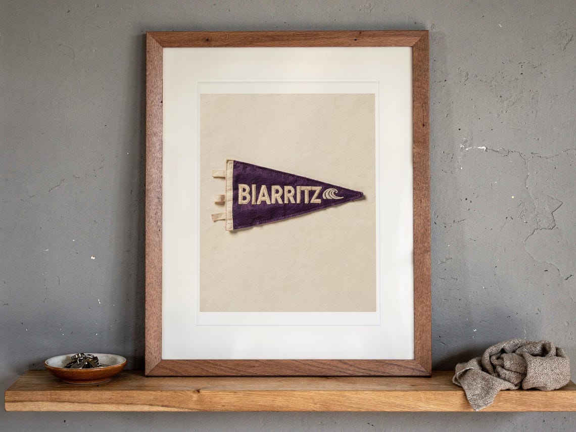 Biarritz print in a Red Oak frame with a white mat, leaning on the ledge against the wall in a hallway.