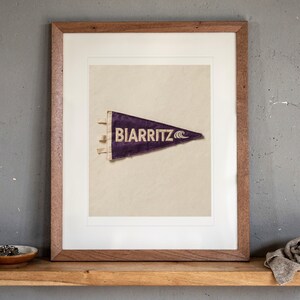 Biarritz print in a Red Oak frame with a white mat, leaning on the ledge against the wall in a hallway.