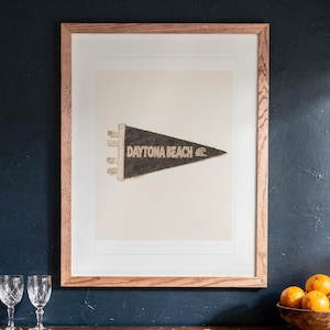 Daytona Beach print in a Red Oak frame with a white mat, hanging above the cabinet in a game room.