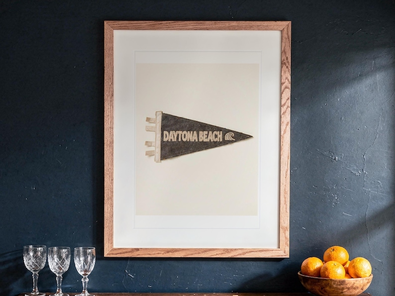 Daytona Beach print in a Red Oak frame with a white mat, hanging above the cabinet in a game room.