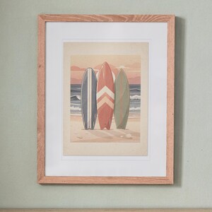 Surfboard Collection Nursery print in a Red Oak frame with a white mat, hanging above the bookshelf in a nursery.