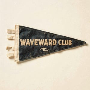 Full Waveward Club surf pennant artwork on a cream ground, showing the weathered felt texture and stitched lettering