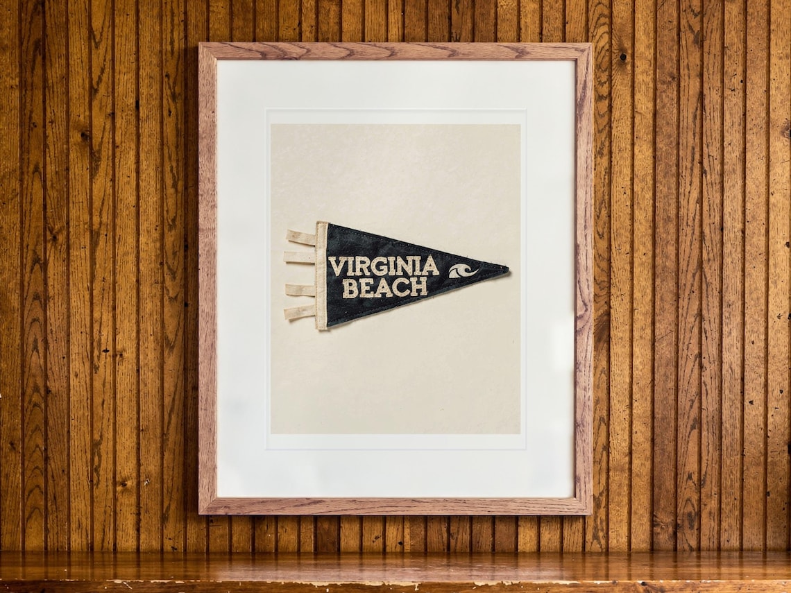 Virginia Beach Surf Pennant print in a Red Oak frame with a white mat, hanging above the credenza in a mid-century living room.