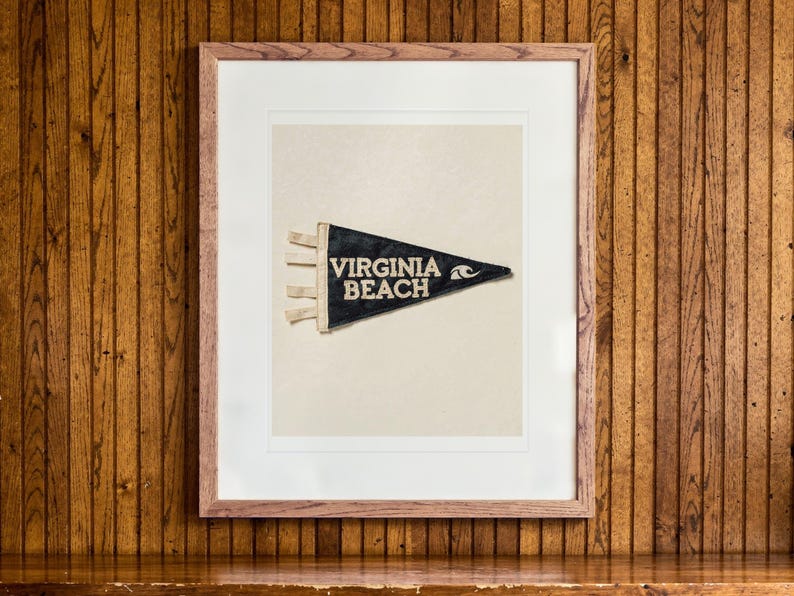 Virginia Beach Surf Pennant print in a Red Oak frame with a white mat, hanging above the credenza in a mid-century living room.