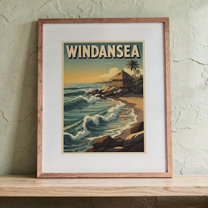 May include: A framed art print featuring a coastal scene with the text WINDANSEA at the top. The illustration depicts a beach with crashing waves, dark rocks, a thatched-roof hut, and palm trees under a soft, warm-toned sunset sky.
