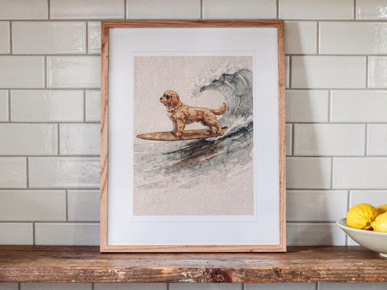 Goldendoodle Surfing printable art, shown printed in a Red Oak frame with a white mat, leaning on the shelf against the wall in a cottage kitchen.