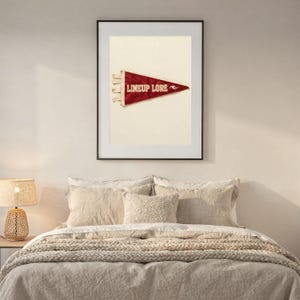 Lineup Lore printable surf pennant styled above a bed in a calm coastal bedroom