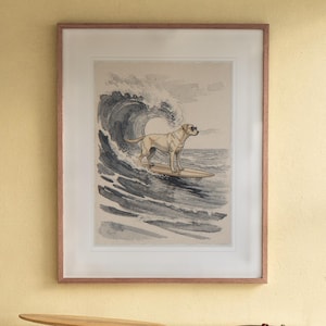Labrador Surfing print in a Red Oak frame with a white mat, hanging above the bookshelf in a kids' room.
