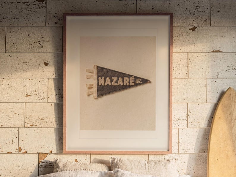 Nazaré Surf Pennant print in a Red Oak frame with a white mat, hanging above the bed in a surf shack bedroom.
