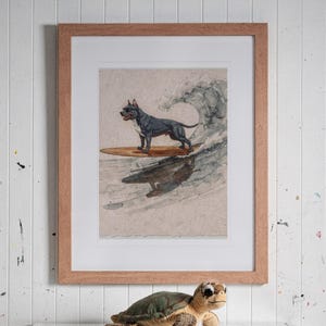 Pit Bull Surfing print in a Red Oak frame with a white mat, hanging above the bookshelf in a kids' room.