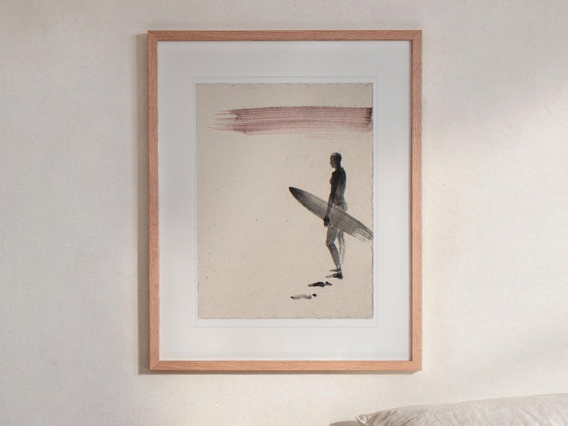 Surfer Ink Style print in a Red Oak frame with a white mat, hanging above the bedside table in a calm bedroom.