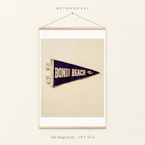 Bondi Beach, Sydney, Australia Surf Pennant oak hanger poster, 24 by 36 inches, with natural wood rails and a hanging cord.