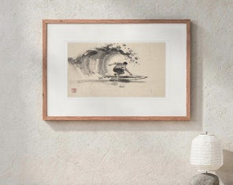 May include: A framed horizontal art print featuring a black ink wash illustration of a surfer riding a large wave. The artwork is set within a white mat and a light brown wooden frame, displaying a small red seal mark in the lower left corner.