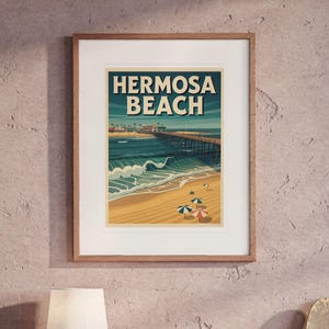 May include: A framed art print featuring a stylised illustration of Hermosa Beach with the text HERMOSA BEACH in bold letters. The image depicts a sandy beach, ocean waves, a long pier, and colourful beach umbrellas under a clear sky.
