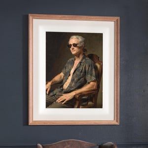 Alexander Hamilton Surfer print in a Red Oak frame with a white mat, hanging on the wall between the shelves in a home library.