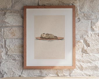 May include: A framed art print featuring a brown sea otter sleeping on a wooden surfboard floating on water. The illustration is set against a light beige background and enclosed in a simple, light-toned wooden frame with a white mat border.