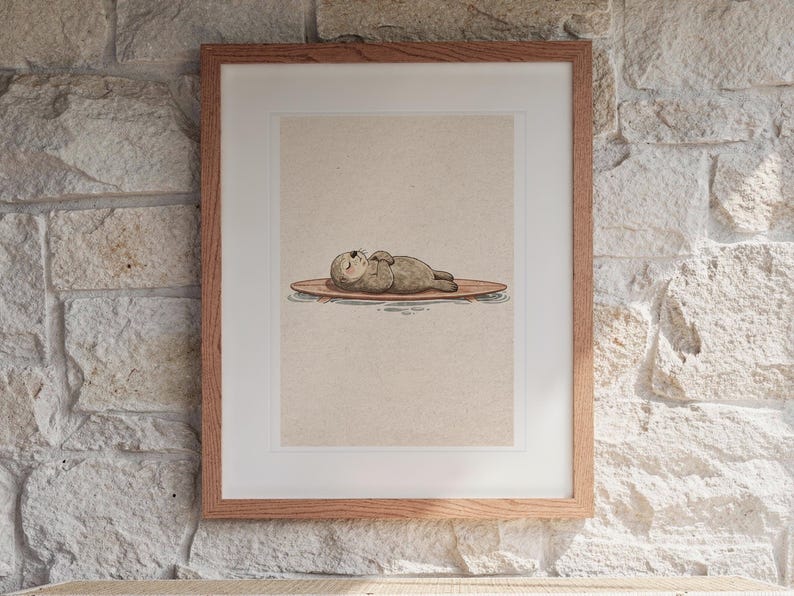 Sea Otter on Surfboard print in a Red Oak frame with a white mat, hanging above the console in a sunroom.