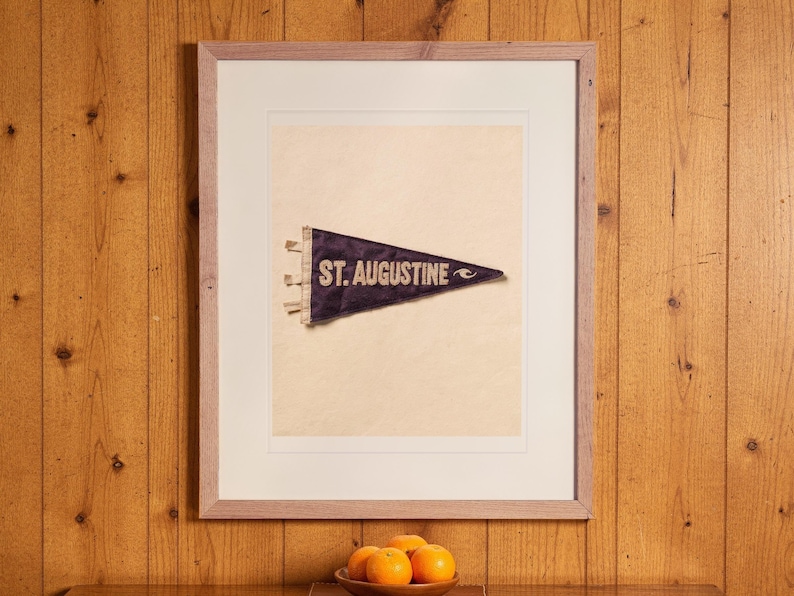 St. Augustine Surf Pennant print in a Red Oak frame with a white mat, hanging above the cabinet in a game room.