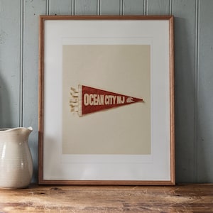 Ocean City print in a Red Oak frame with a white mat, leaning on the counter against the backsplash in a cottage kitchen.