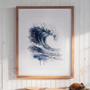 May include: A framed watercolor painting of a large, crashing ocean wave in shades of deep blue, navy, and white. The artwork is centered within a light-toned wooden frame, featuring expressive paint splatters and fluid, layered brushstrokes.