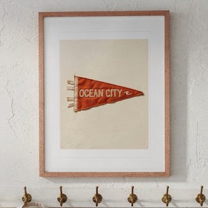 Ocean City print in a Red Oak frame with a white mat, hanging above the bench in a beach cottage entryway.